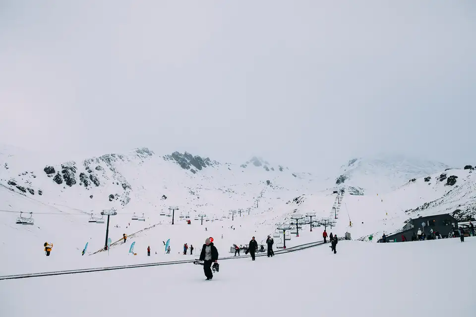 Skiers on the snow at The Remarkables ski area with the range rising behind