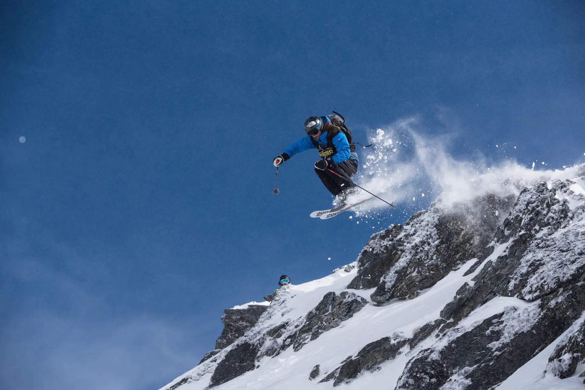 Freeride skier launching from a snowy ridge at The Remarkables