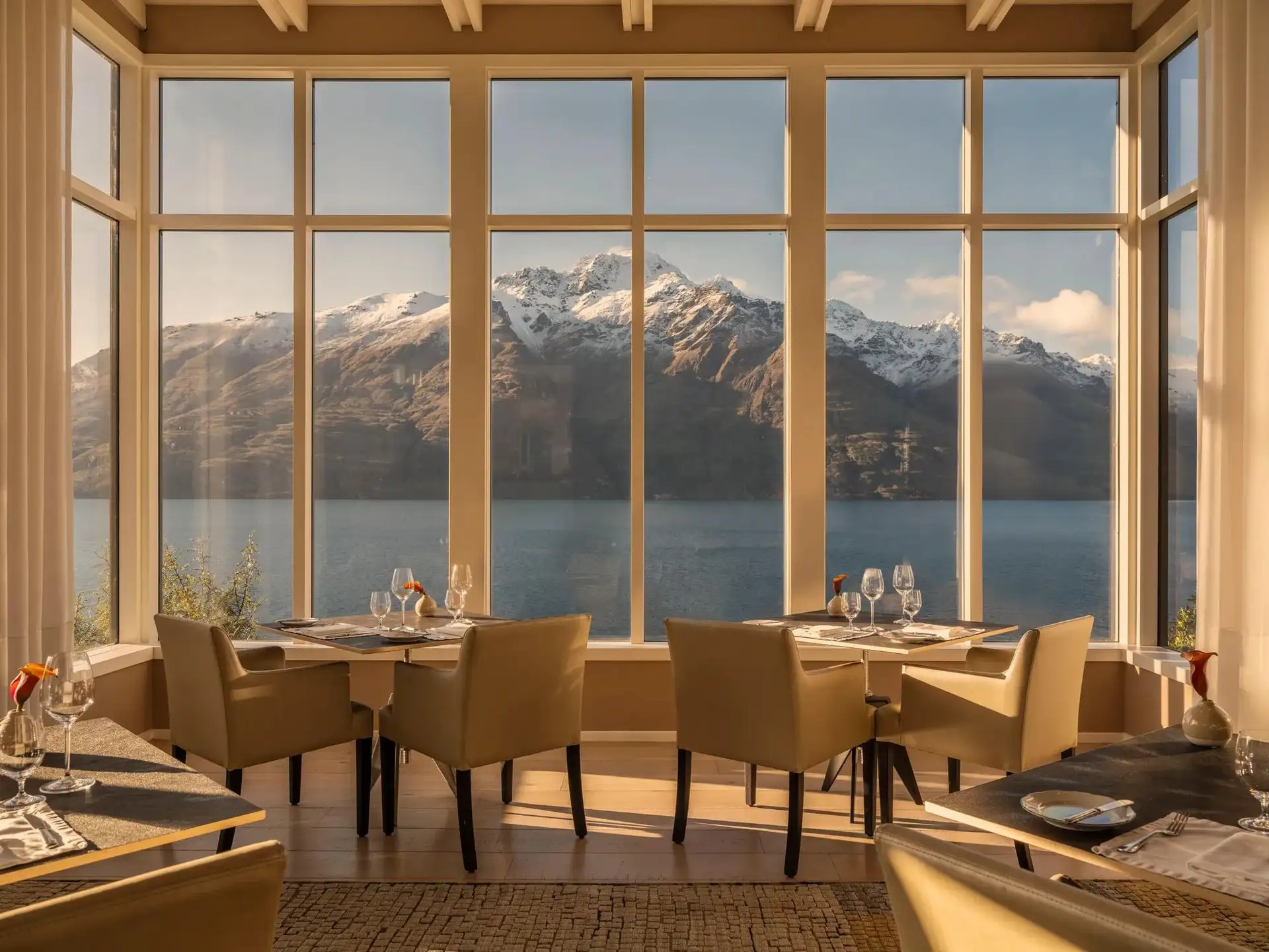 Tables by the windows in the main dining room at Rosewood Matakauri, looking over Lake Whakatipu