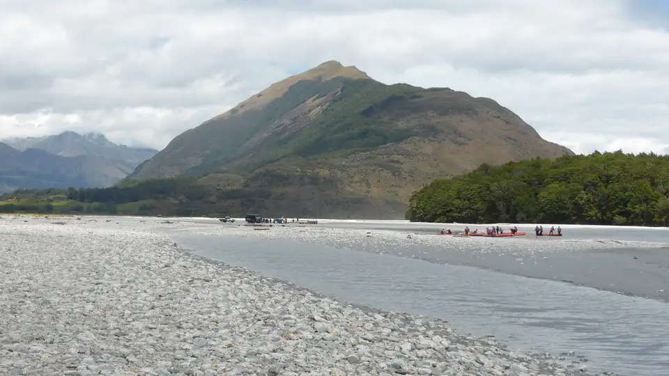 The braided grey riverbed of the Dart River below cloud-covered mountains near Glenorchy