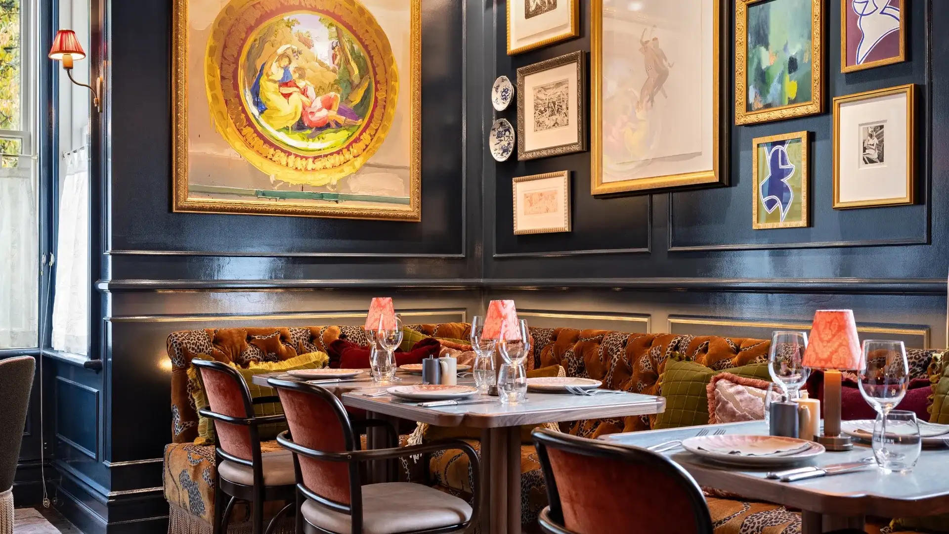 The navy-panelled dining room at Billy's, hung with gilt-framed pictures above a tan velvet banquette and set tables