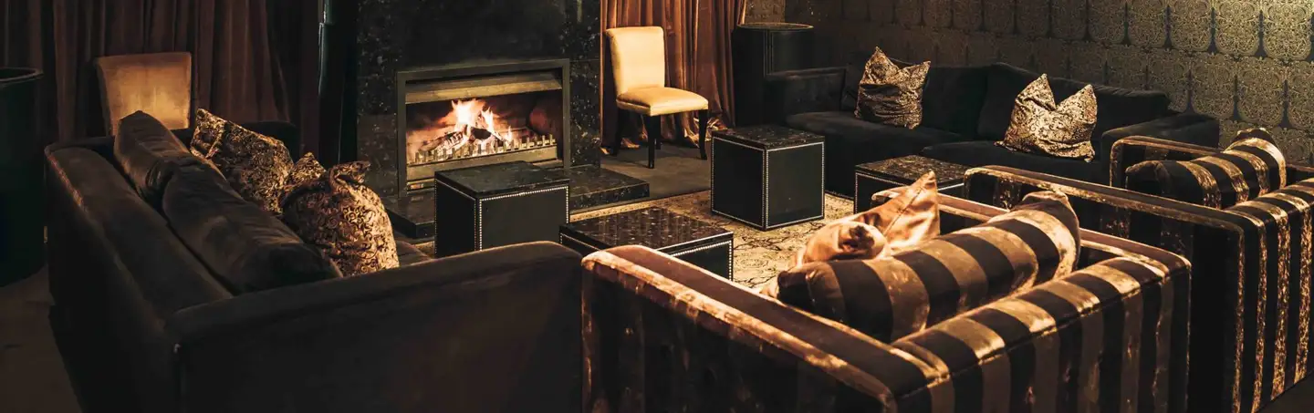 A lounge at Botswana Butchery with leather sofas and armchairs drawn up to an open log fire.