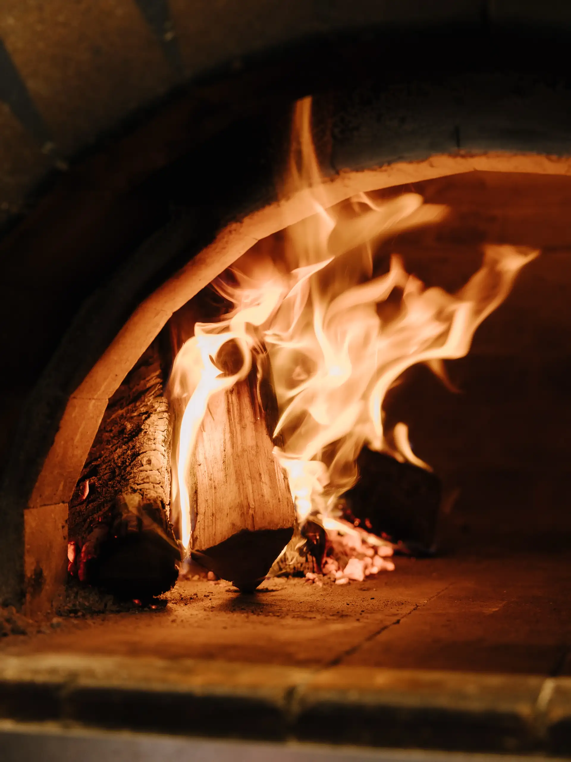 Flames rising from burning logs inside the wood-fired oven at Sundays.