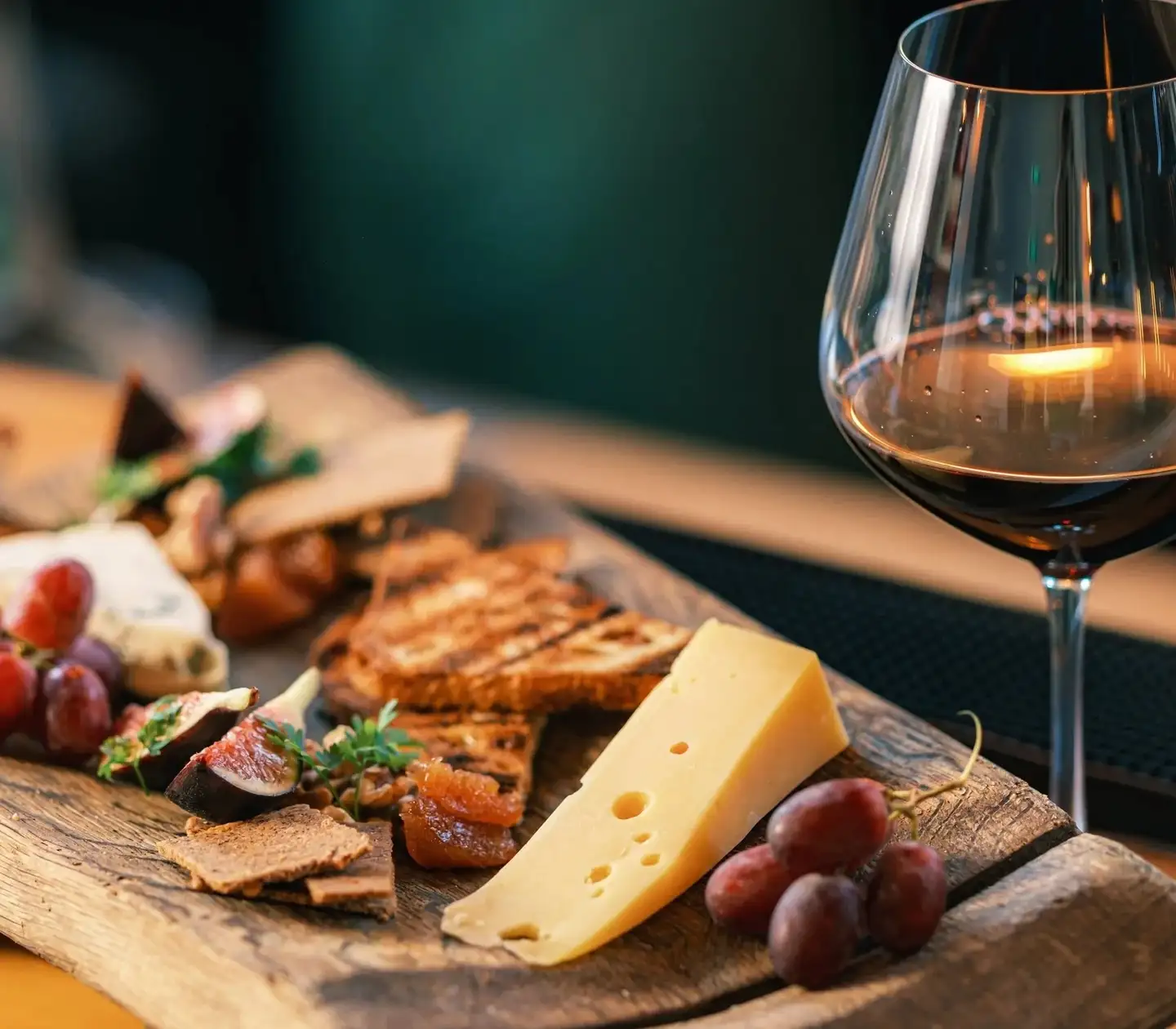 A wooden board of cheese, grapes, grilled bread and charcuterie beside a glass of red wine at Prospects.