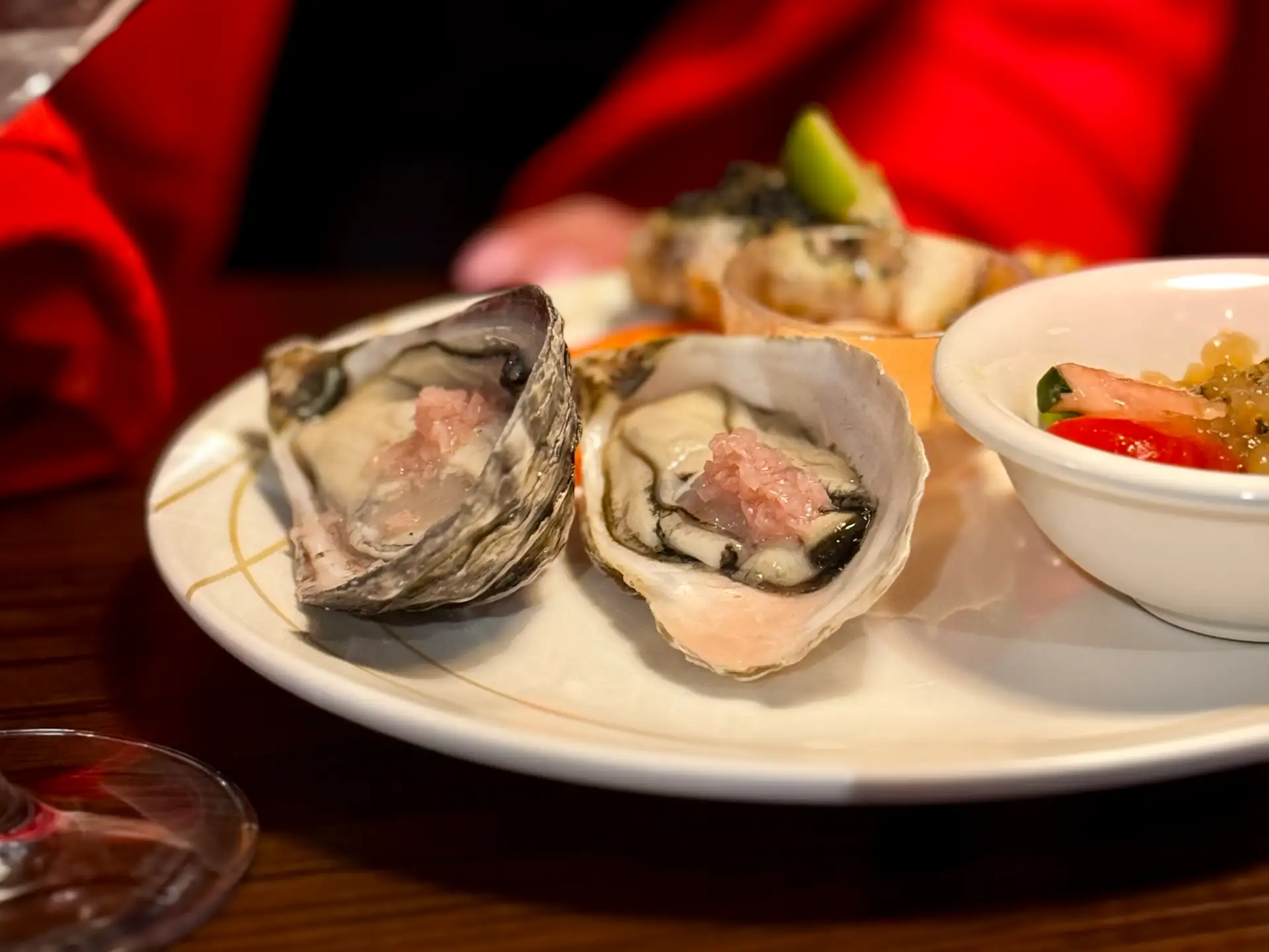 Two large raw Marlborough oysters on a plate beside a small bowl of ika mata at Prospects.