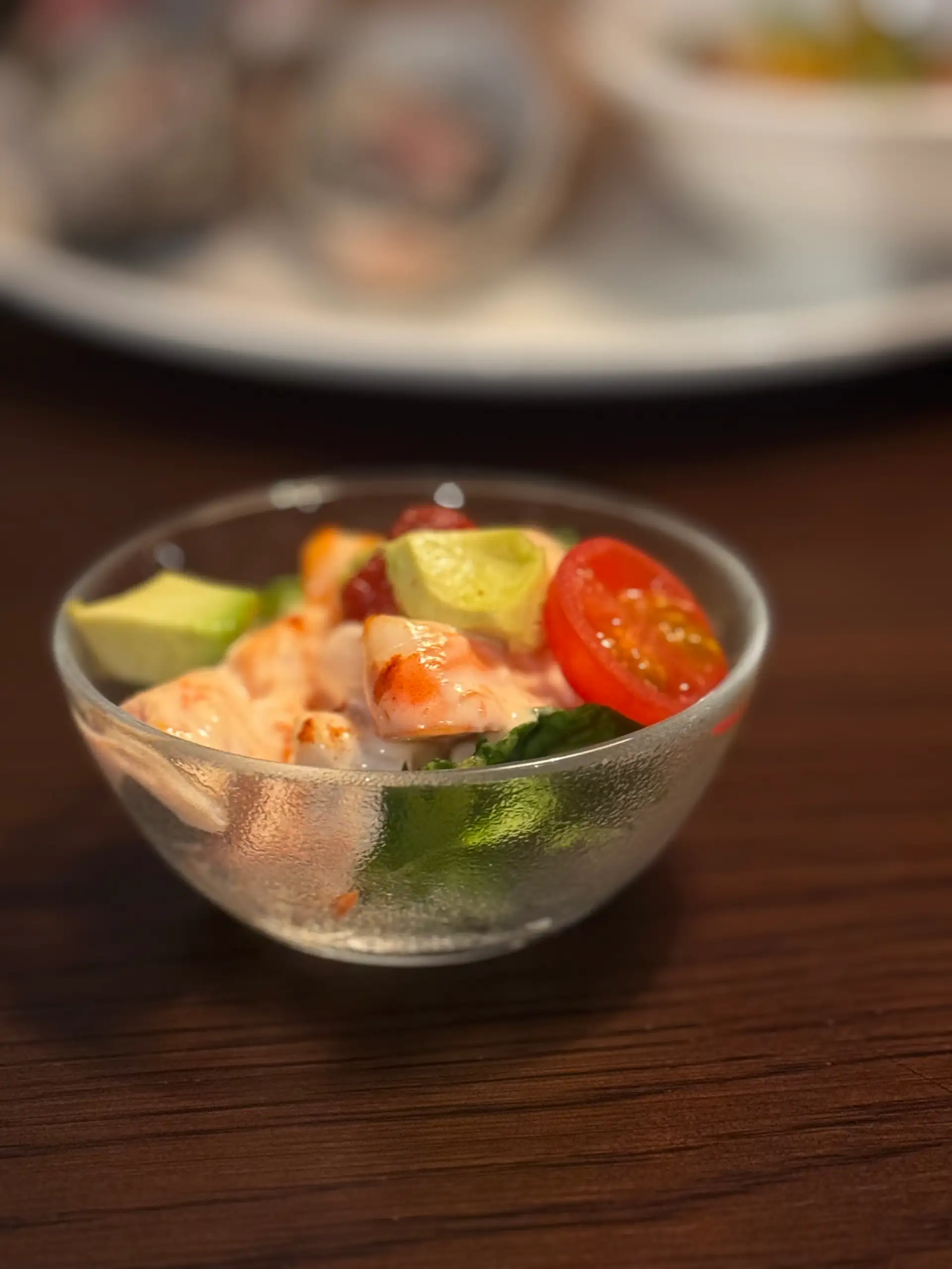 A glass bowl of ginger prawn cocktail with avocado, cherry tomato and lettuce on a timber table at Prospects.