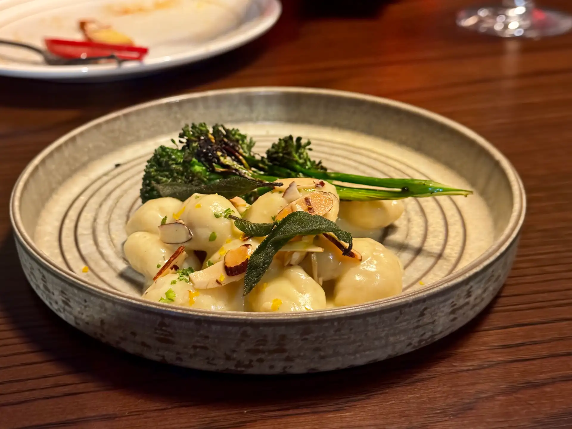 Four-cheese gnocchi with wood-fired broccolini, sage leaves and shaved almonds in a stoneware bowl at Prospects.