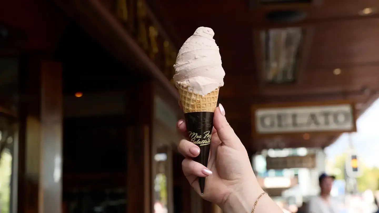A Mrs Ferg gelato cone held up outside the shop, with its Gelato sign behind